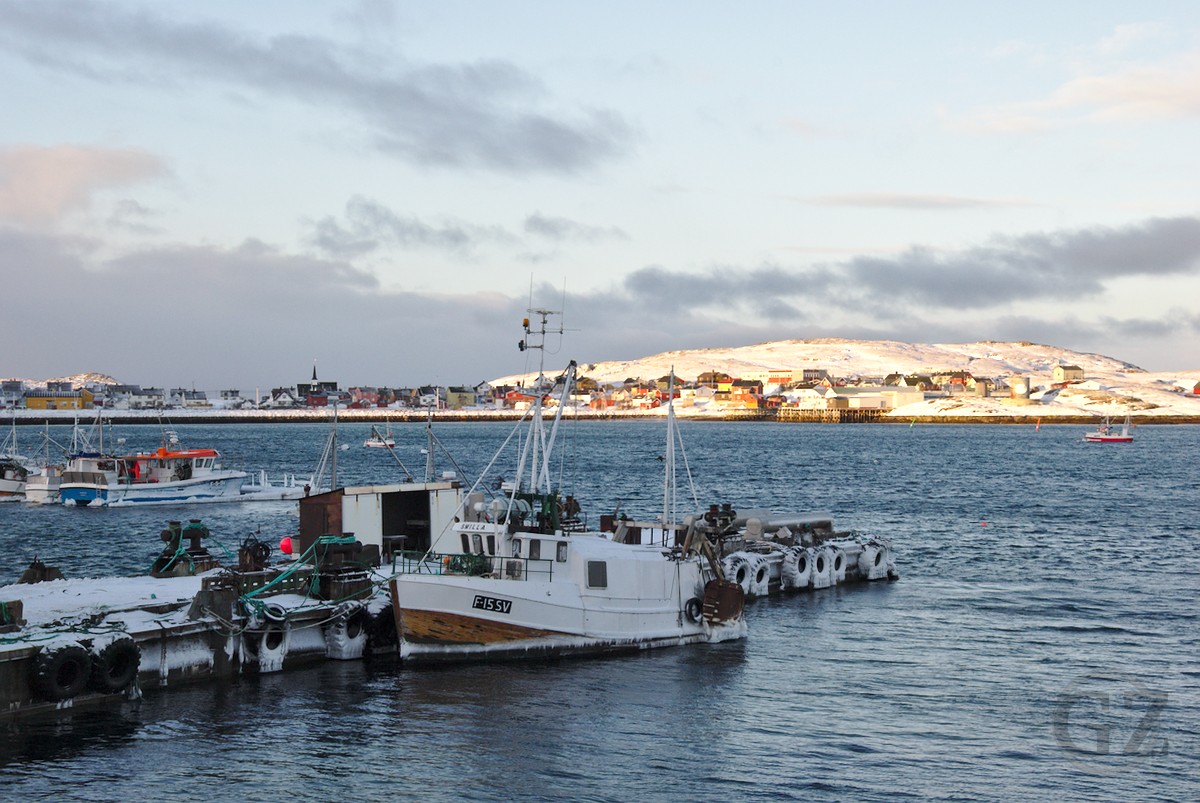 Boat with frozen water in open sea with village in background