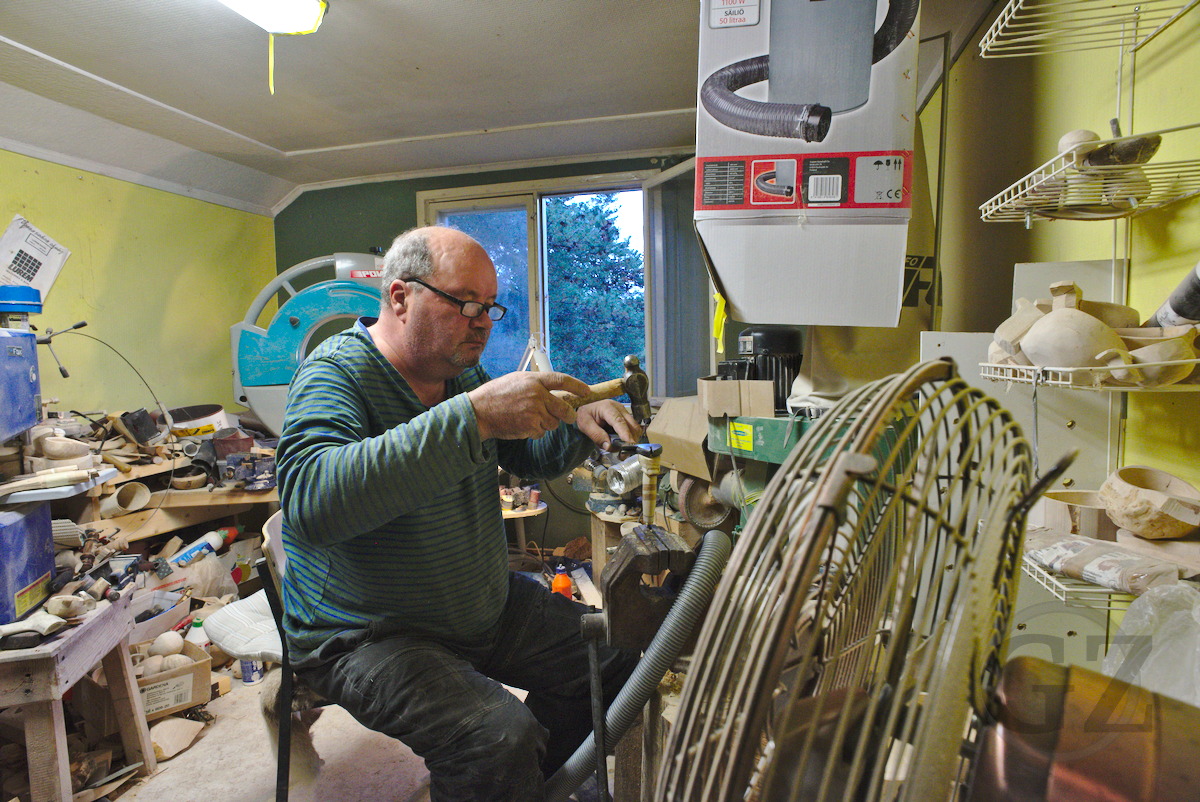 man sitting in work shop, smoothening wood on a machine