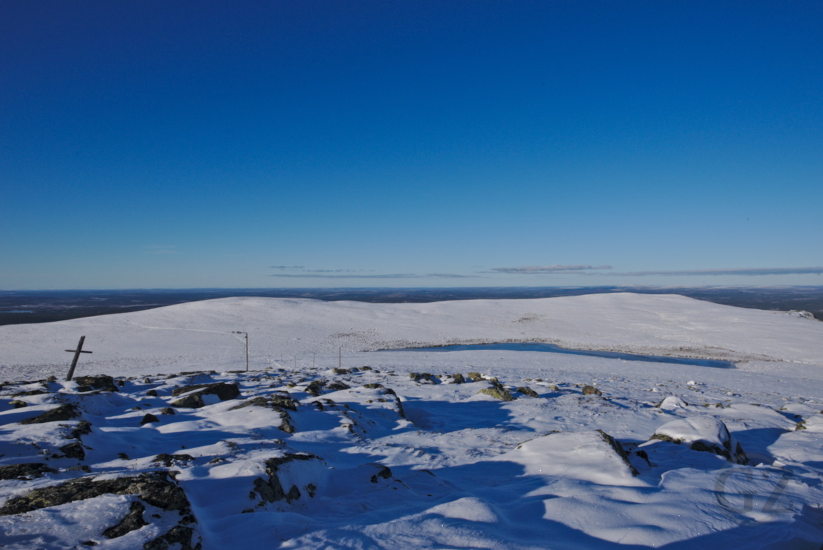 Partly frozen, small lake on top of snow covered fell