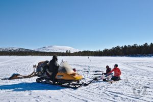 people fishing on frozen lake with fell in background