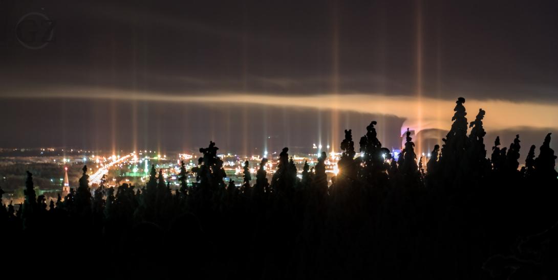 light rising stright into sky from city lighting