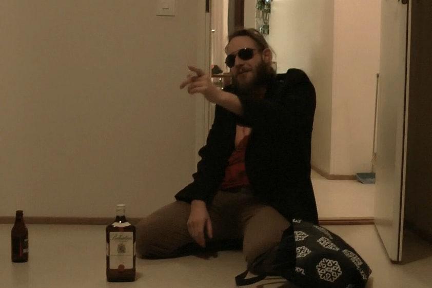 Santa Claus person wearing sun glasses in front of whiskey bottle